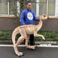 Load image into Gallery viewer, Person holding a model of a dinosaur-like creature on a street.