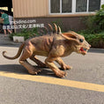 Carica l'immagine nel visualizzatore della galleria, A realistic dinosaur toy or prop dinosaur standing on an outdoor paved surface in front of a building, with visible people and plants in the background. The dinosaur is tan and brown with darker ridged spikes along its back and an open mouth showing red teeth.