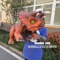 Load image into Gallery viewer, Person wearing a dinosaur costume holding a large dinosaur model outdoors.
