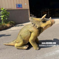 Load image into Gallery viewer, A realistic baby Triceratops dinosaur toy or prop shown outdoors on asphalt in front of a building. The toy has textured olive-green and tan skin, small horns, and a horned head crest.