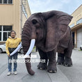 Charger l'image dans la visionneuse de la galerie, Person standing next to a large elephant costume in an urban setting