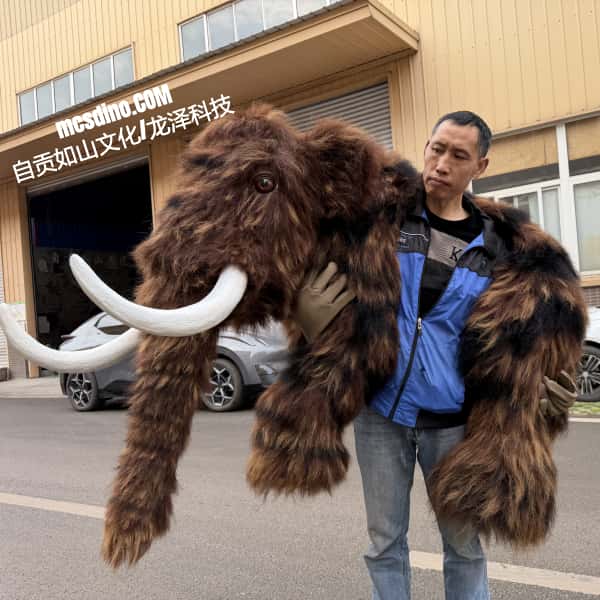 Person holding a large fluffy mammoth costume in front of a building with visible text.