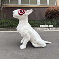 Load image into Gallery viewer, White dinosaur-like creature with red and black eye design on a road.
