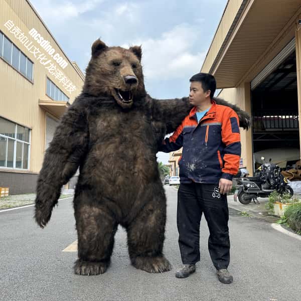 Person interacting with a large bear costume on a street.
