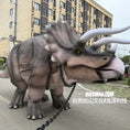 Load image into Gallery viewer, Dinosaur model on a chain in an urban setting with buildings in the background
