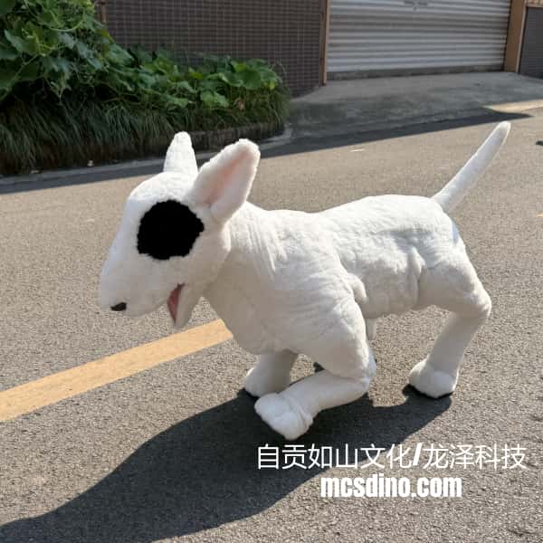 A white bull dog plush toy with a black patch on its face, standing on an asphalt street outdoors.