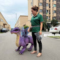 Cargar la imagen en la vista de la galería, Person standing next to a purple dinosaur costume on a street.
