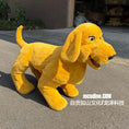 Load image into Gallery viewer, A yellow plush dog costume or stuffed animal toy standing on an outdoor paved surface, with a building and plants in the background. White Chinese text watermark is visible near the bottom right.
