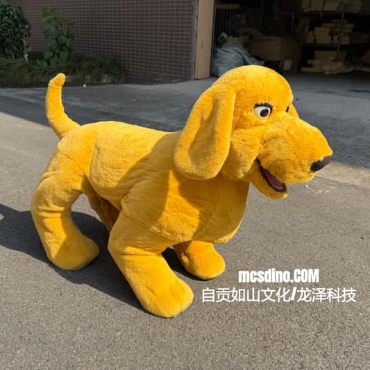 A yellow plush dog costume or stuffed animal toy standing on an outdoor paved surface, with a building and plants in the background. White Chinese text watermark is visible near the bottom right.
