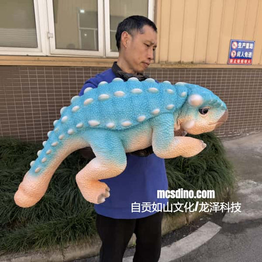 Person holding a large blue and pink plush dinosaur toy outdoors.