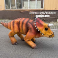 Load image into Gallery viewer, A realistic animatronic dinosaur toy, specifically a Triassic period dinosaur with orange and black stripes, walking on an outdoor paved surface in front of a building.
