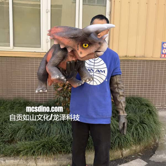 Person holding a dinosaur model in front of a building