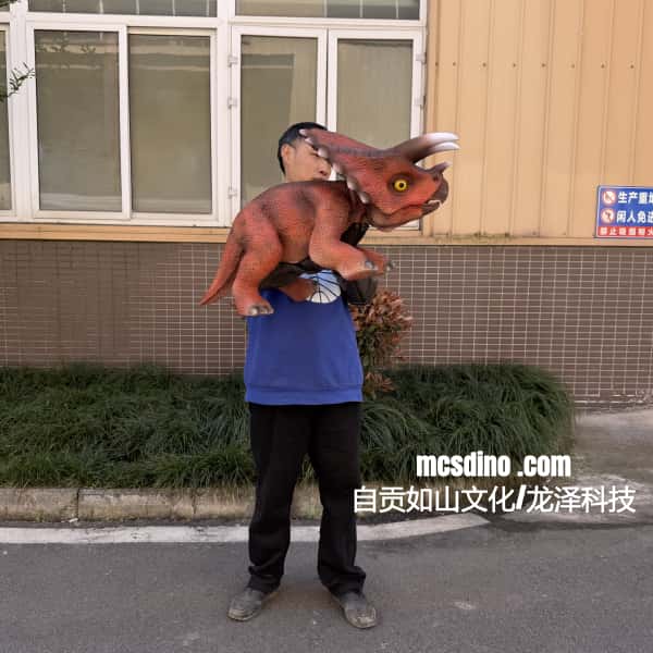 Person holding a dinosaur costume in front of a building