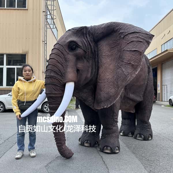 Person standing next to a large elephant costume in an urban setting