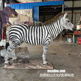 Carica l'immagine nel visualizzatore della galleria, A life-size zebra animal statue or model displayed indoors in a workshop or showroom. The zebra stands on a base in profile, with black-and-white stripes, a brown mane, and visible wiring underneath.
