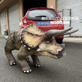 Cargar la imagen en la vista de la galería, Dinosaur costume UNITREE GO2  in front of a red car with visible text.

